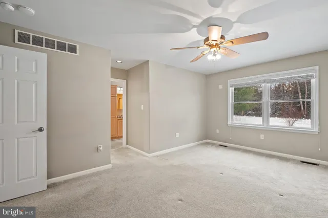 an empty room with windows and fan