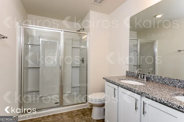 a bathroom with a granite countertop sink toilet and shower