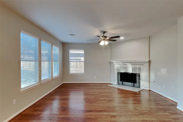 a view of an empty room with wooden floor fireplace and a window