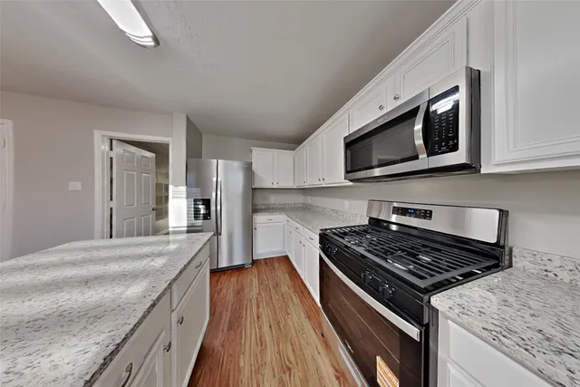 a kitchen with stainless steel appliances granite countertop a stove microwave and sink