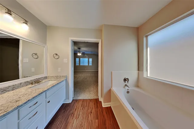 a spacious bathroom with a granite countertop tub sink and mirror