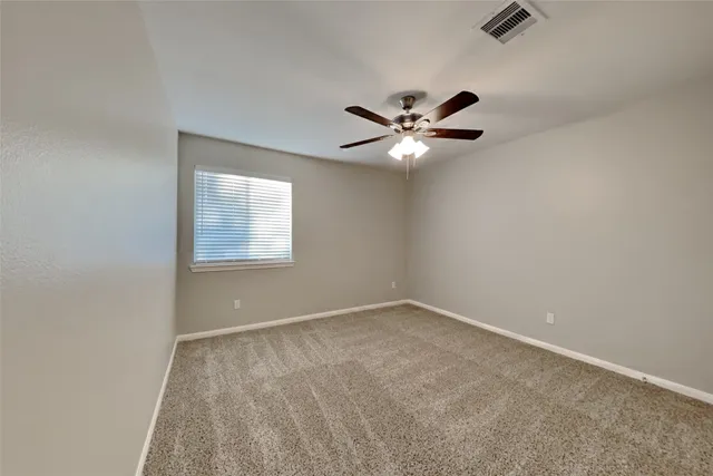 an empty room with a chandelier fan and windows