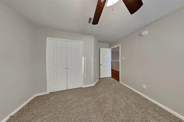an empty room with ceiling fan and window