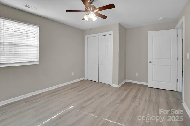 an empty room with wooden floor closet and windows