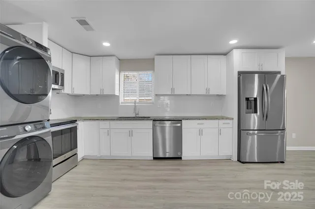 a kitchen with granite countertop a sink a stove a refrigerator and cabinets