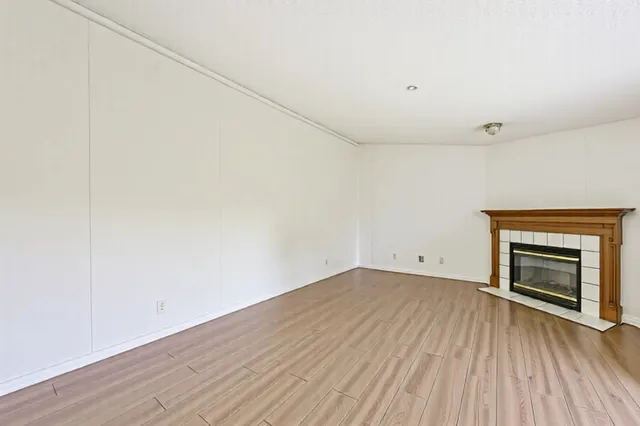 a view of empty room with wooden floor and fireplace