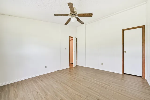 an empty room with wooden floor and ceiling fan