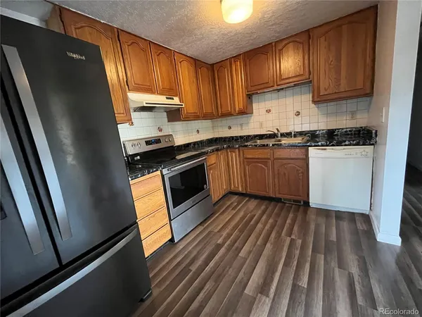 a kitchen with granite countertop wooden cabinets a sink and a stove