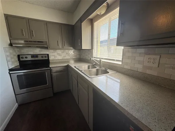 a kitchen with granite countertop a sink a stove and cabinets