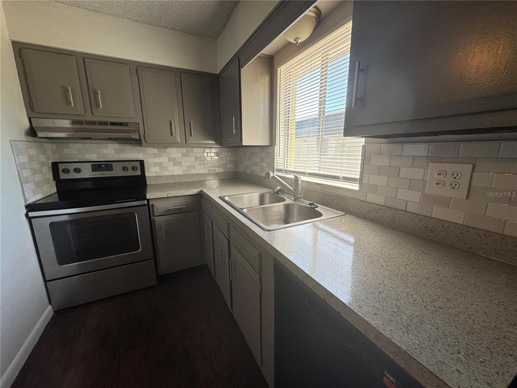 525 South Conway Road, Unit 220 Orlando, FL 32807 - Photo 5 of 12 a kitchen with granite countertop a sink a stove and cabinets