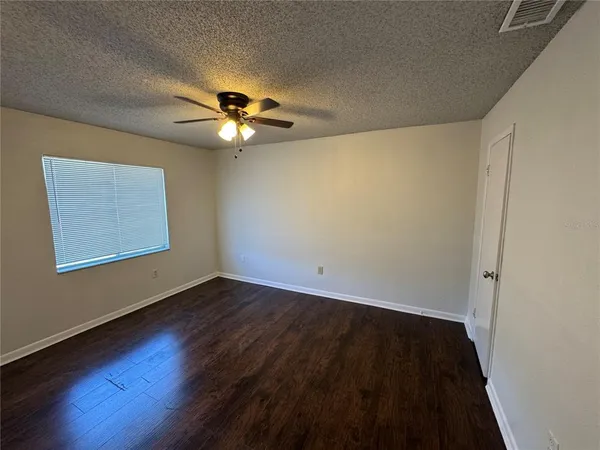 a view of an empty room with a window and wooden floor