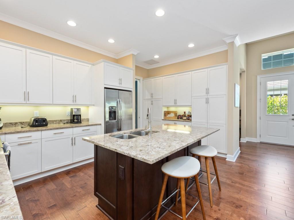 5697 Highbourne Drive Naples, FL 34113 - Photo 12 of 35 a kitchen with stainless steel appliances granite countertop a table chairs sink and cabinets