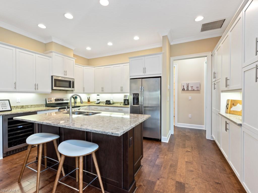 5697 Highbourne Drive Naples, FL 34113 - Photo 10 of 35 a kitchen with stainless steel appliances granite countertop a sink a stove a refrigerator and island with wooden floor