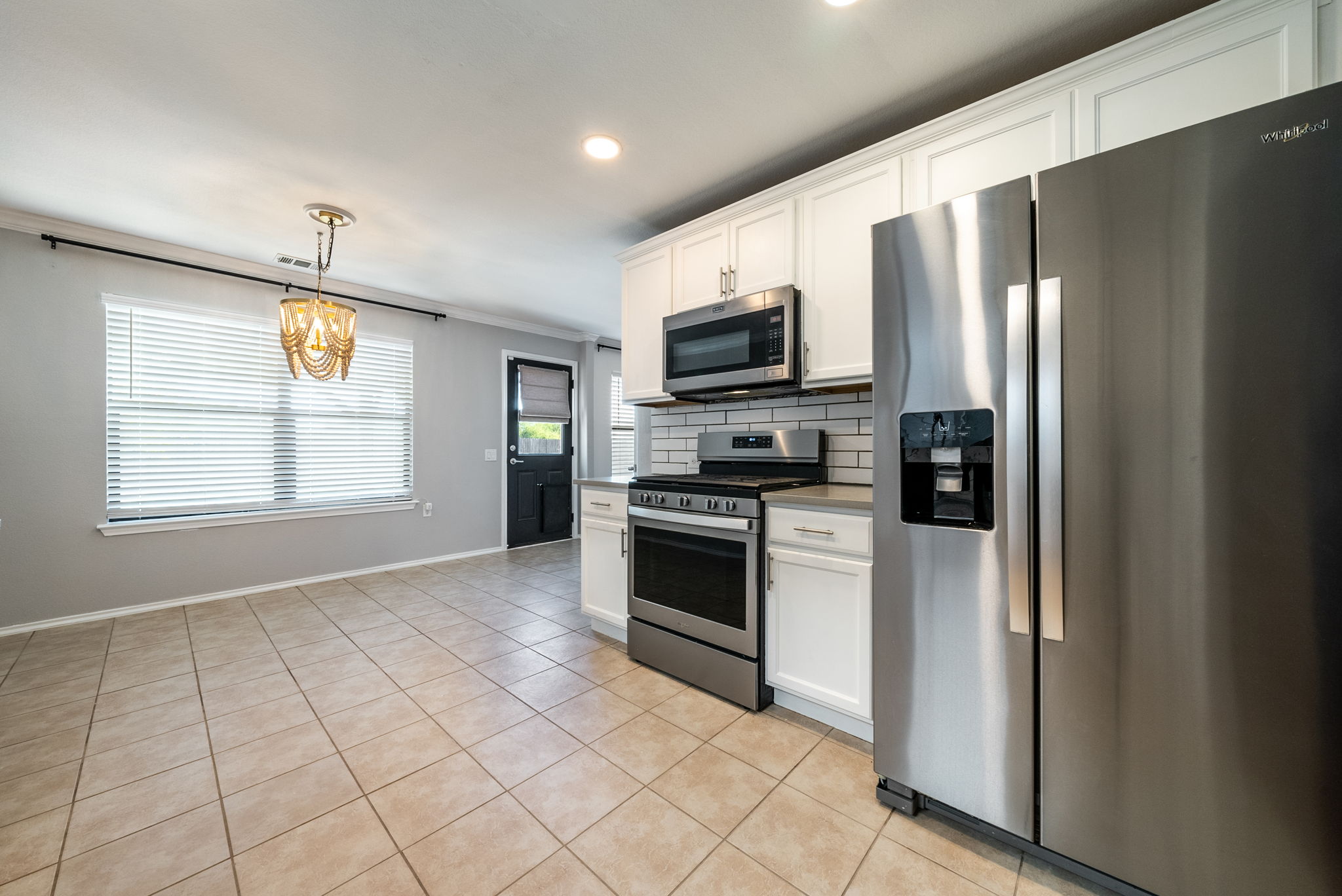 7124 Outfitter Drive Austin, TX 78744 - Photo 10 of 25 a kitchen with stainless steel appliances a refrigerator a stove a microwave and a window
