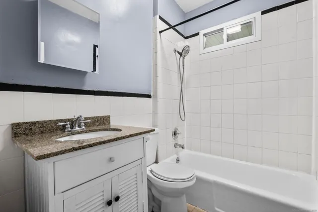 a bathroom with a granite countertop sink a toilet and bathtub