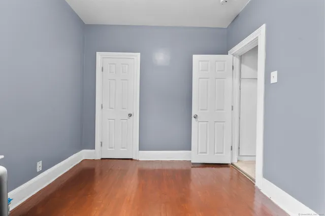 a view of an empty room with wooden floor and closet