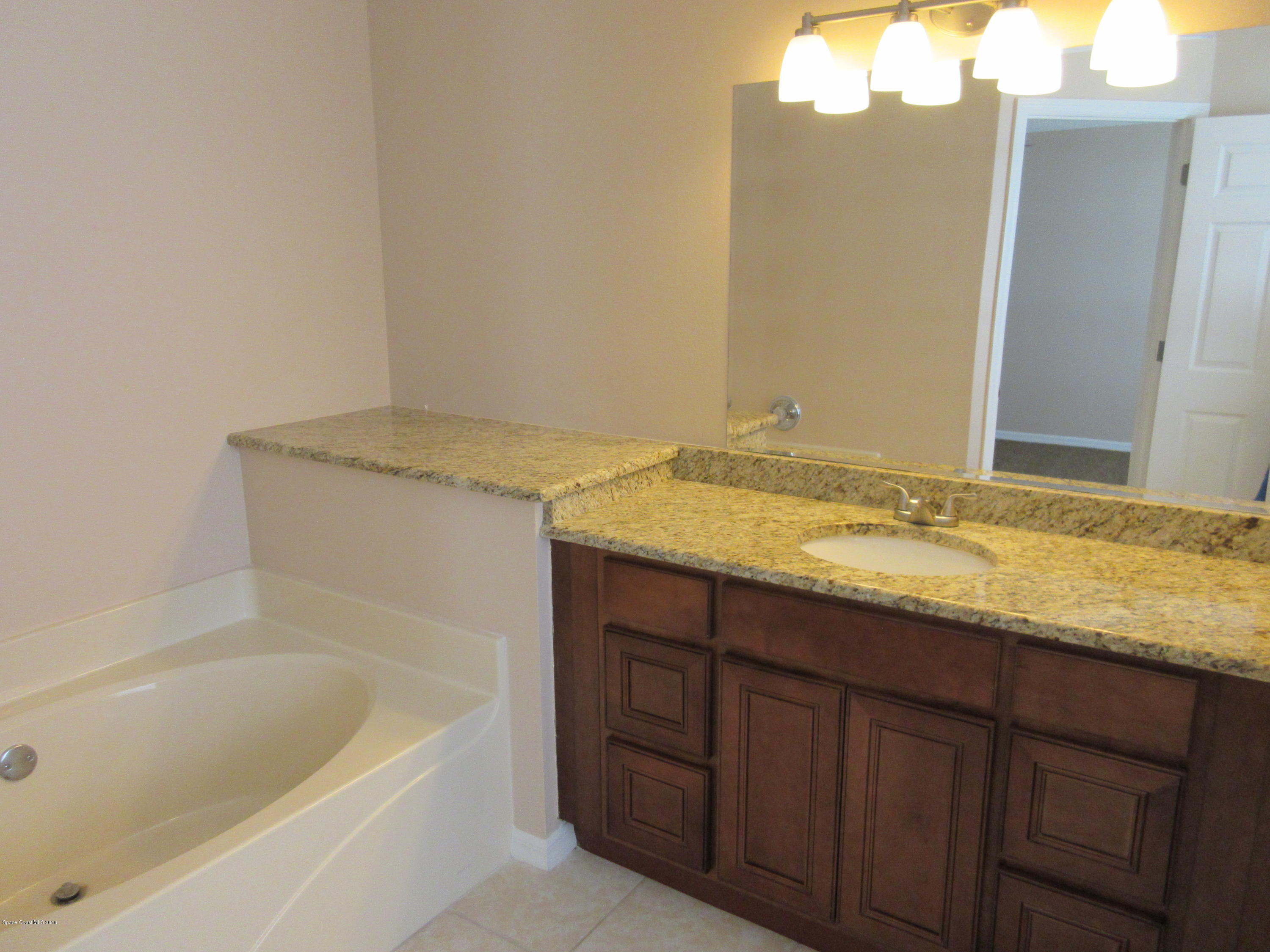 441 Wildmer Road Southwest Palm Bay, FL 32908 - Photo 32 of 67 a bathroom with a granite countertop sink and a bathtub