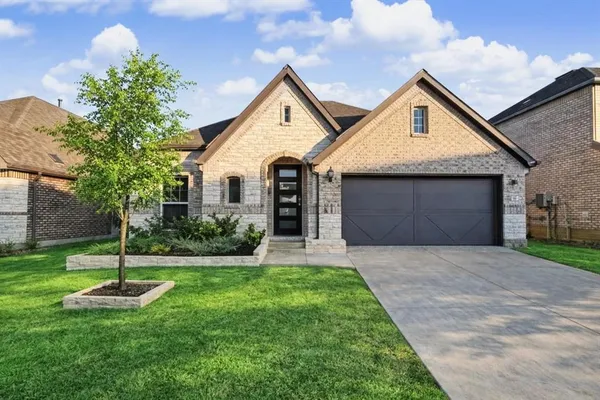 a front view of a house with a garden and trees