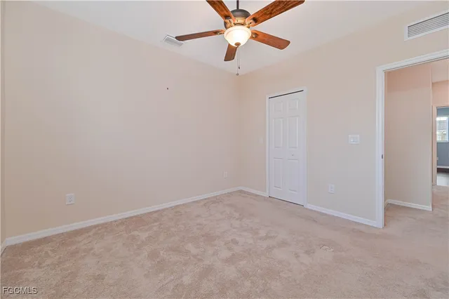 an empty room with closet and a chandelier fan