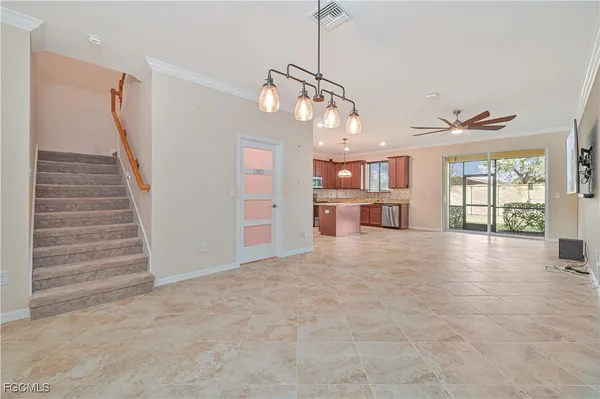 a view of an empty room with a window and kitchen view