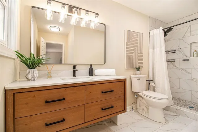 a bathroom with a granite countertop sink toilet a large mirror and shower