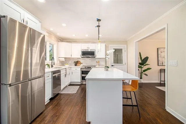 a kitchen with a refrigerator a sink dishwasher and a stove with wooden floor