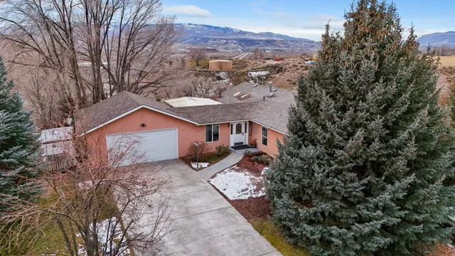 a front view of a house with a yard and mountain view in back