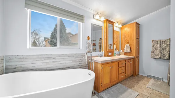 a bathroom with a tub a sink and a large mirror next to a window