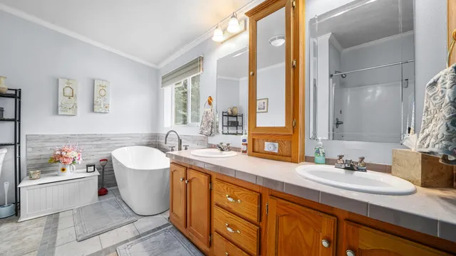 a spacious bathroom with a granite countertop sink a mirror a bathtub and a window