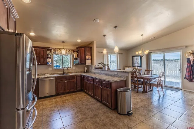 a kitchen with stainless steel appliances granite countertop a stove top oven a sink dishwasher a dining table and chairs with wooden floor