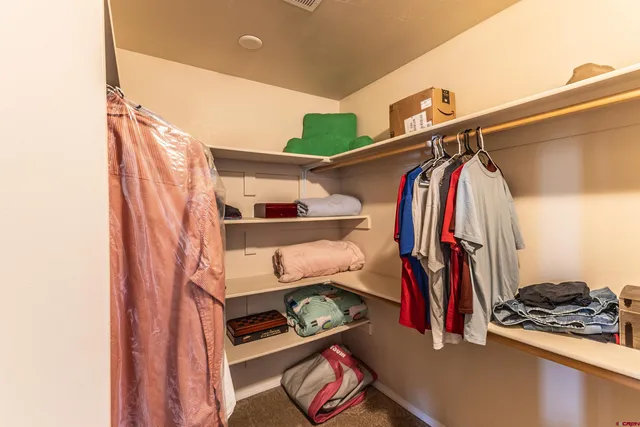 a view of walk in closet with clothes and shoes