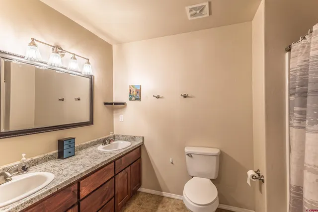 a bathroom with a granite countertop sink toilet and mirror
