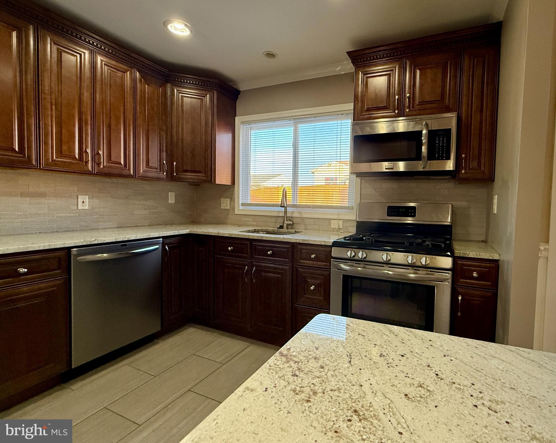 900 Southridge Road Catonsville, MD 21228 - Photo 13 of 31 a kitchen with stainless steel appliances granite countertop wooden cabinets a stove top oven a sink and dishwasher