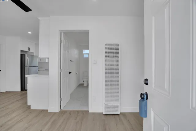 a view of an empty room with wooden floor and a kitchen