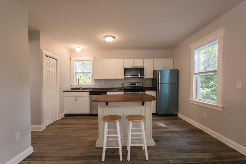 1570 County Street Somerset, MA 02726 - Photo 7 of 21 a kitchen with a refrigerator a stove a sink and white cabinets with wooden floor