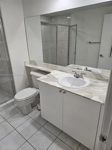 a bathroom with a granite countertop sink a toilet a mirror and shower