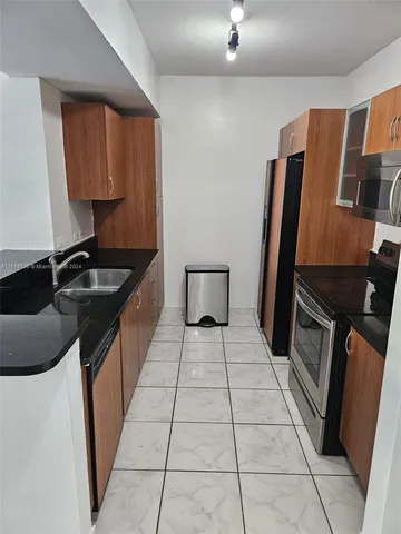a kitchen with stainless steel appliances kitchen island granite countertop a sink and a refrigerator