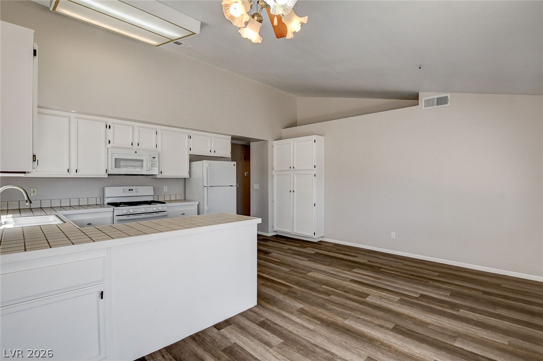 6209 Warm River Road Las Vegas, NV 89108 - Photo 13 of 39 An inviting open-concept kitchen features a peninsula with counter seating and a dining area with wood flooring.