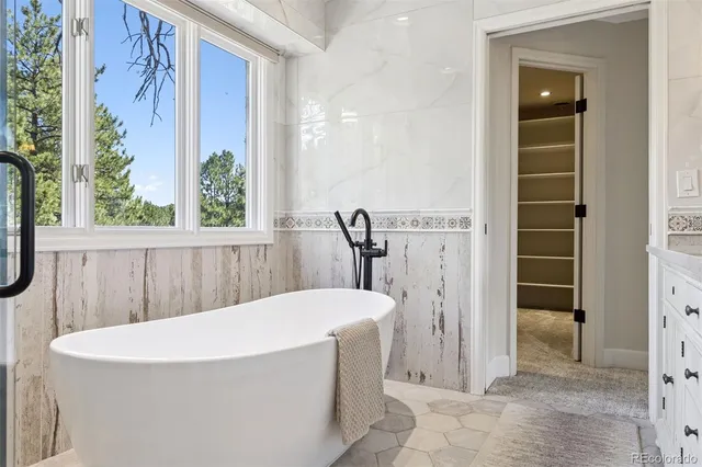 a white bath tub sitting in a bathroom next to a window