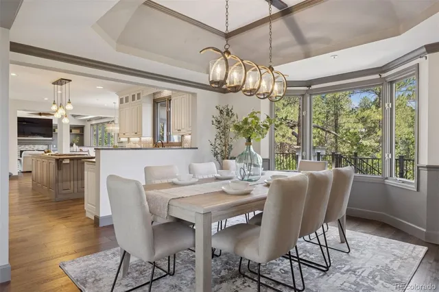 a dining room with wooden floor a chandelier a wooden table and chairs