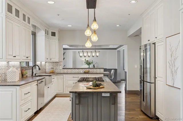 a kitchen with stainless steel appliances granite countertop a sink a stove a refrigerator and island with wooden floor