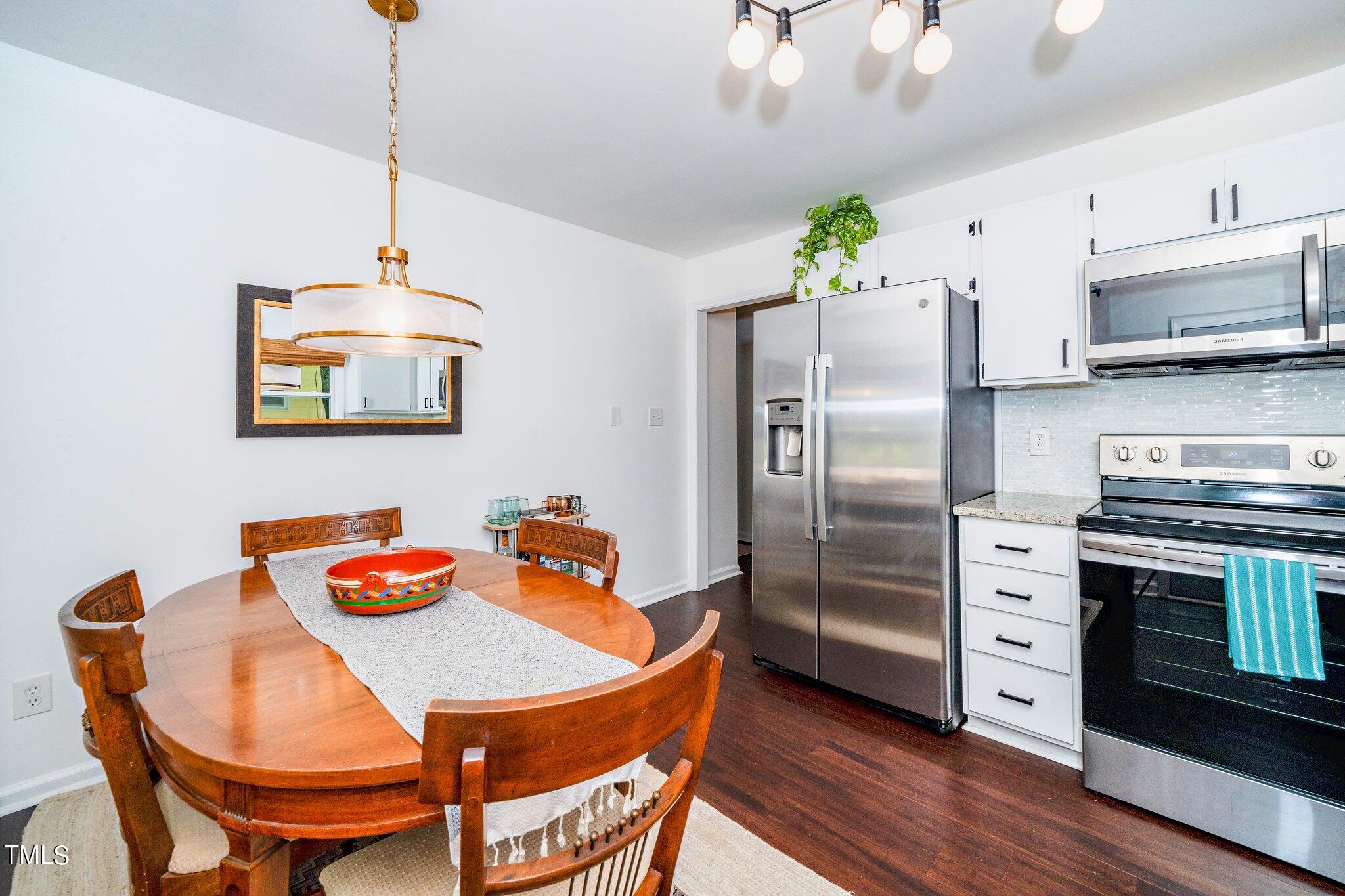 7 Little Spring Lane Durham, NC 27707 - Photo 13 of 25 a kitchen with stainless steel appliances granite countertop a refrigerator a stove a microwave a dining table and chairs with wooden floor