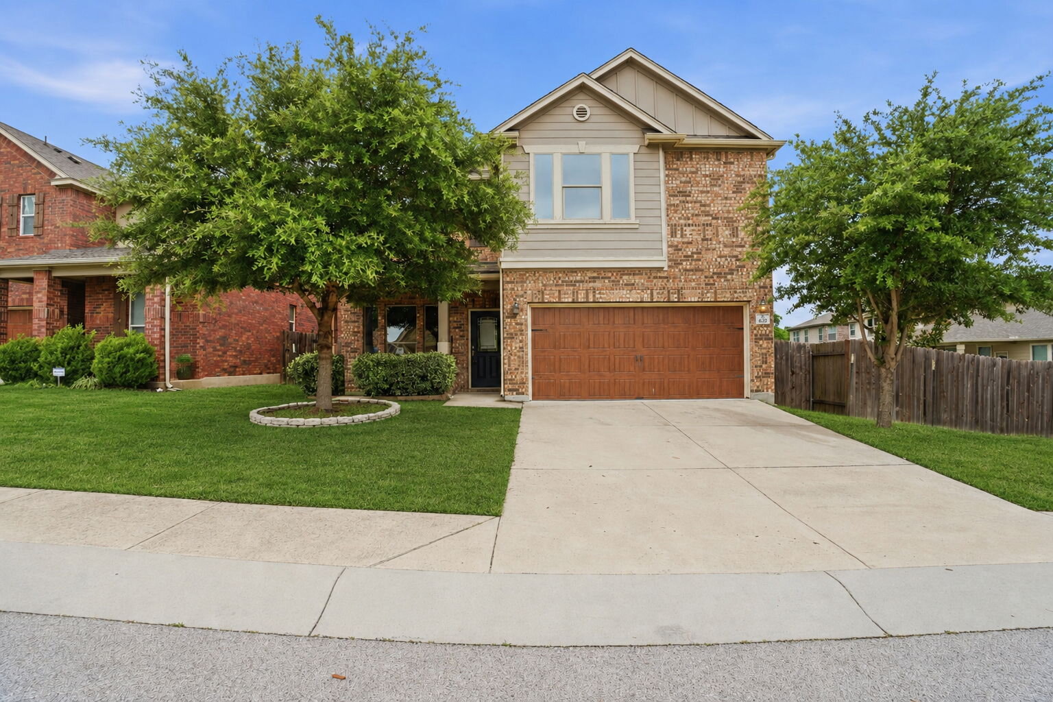 670 Landon Samuel Loop Pflugerville, TX 78660 - Photo 1 of 22 Two-story residence featuring a stone and siding facade, a two-car garage with a wood-finish door, and mature landscaping