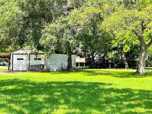 a view of a house with a big yard and large trees