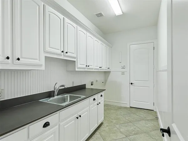 a kitchen with white cabinets and sink