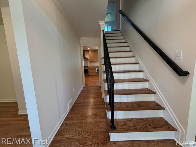 971 Canterbury Road Grosse Pointe, MI 48236 - Photo 10 of 30 Hardwood flooring, painted white walls, white crown molding, wood-finish staircase treads, and a black wrought iron stair railing