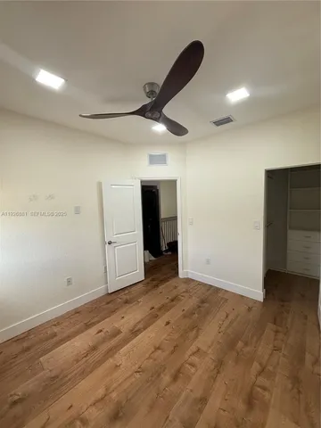 an empty room with wooden floor closet and windows