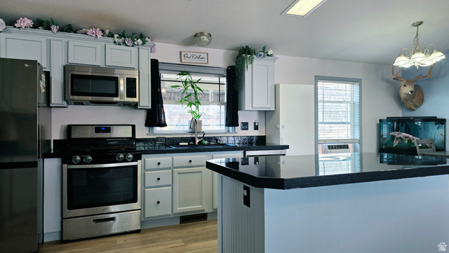401 West 2000th Street South Vernal, UT 84078 - Photo 5 of 26 Kitchen featuring light-toned cabinetry, stainless steel appliances, black countertops, a matching black tile backsplash, and wood-finish flooring