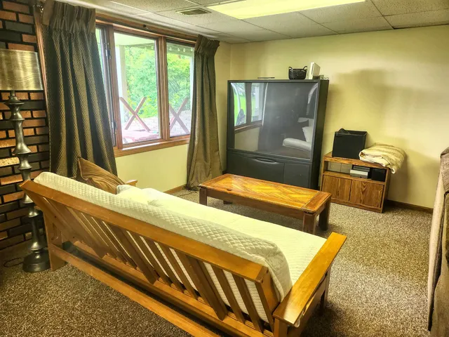 a bedroom with a bed dresser and a large window