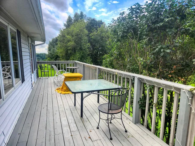 a balcony with wooden floor table and chairs